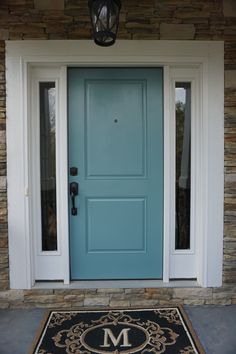 a blue front door with the letter m on it and a welcome mat in front