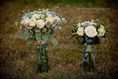 two vases filled with white and blue flowers on top of green grass next to each other