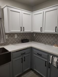 a kitchen with white cabinets and gray counter tops