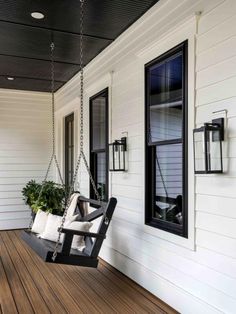 a porch swing is hanging from the side of a white house with black shutters