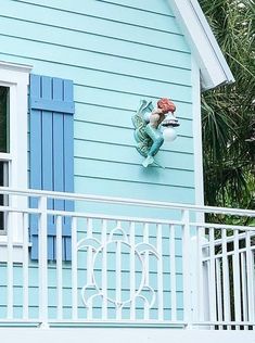 there is a blue house with a crab on the wall and a white porch railing