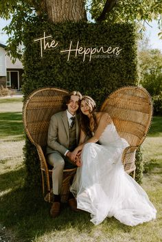 a bride and groom sitting on a wicker chair in front of a sign that says the happiness