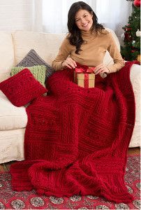 a woman sitting on a couch holding a red blanket and wrapped in a gift box