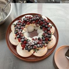 a cake with berries and cream on it sitting on a plate next to silverware