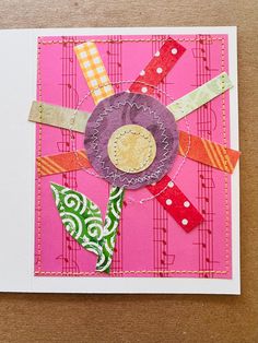 a pink card with a flower made out of strips of paper on top of it