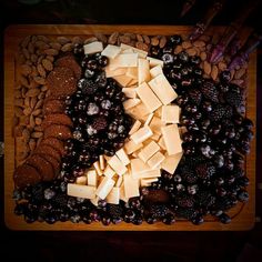 cheese, grapes and nuts are arranged on a cutting board