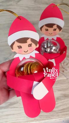 an ornament in the shape of two elfs with coins inside it and on top of each other