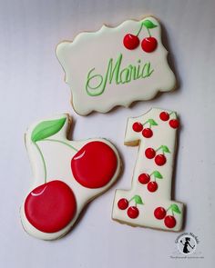 two decorated cookies sitting on top of a white table next to the number one cookie