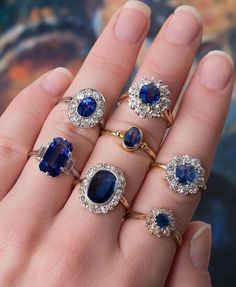 a woman's hand with five different rings and one has blue stones on it