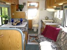 the interior of an rv with wood paneling and white counter tops, couches, and sink