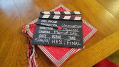 a wooden table topped with a black and white movie clapper on top of a red napkin