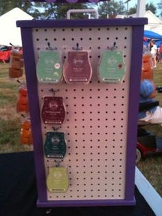 a purple and white display case with tags on it at an outdoor event in the grass