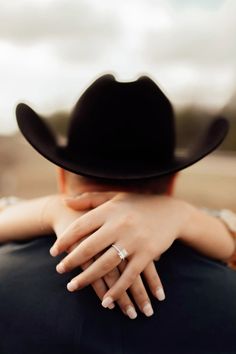 a man in a black cowboy hat hugging a woman's back with her hand on his shoulder