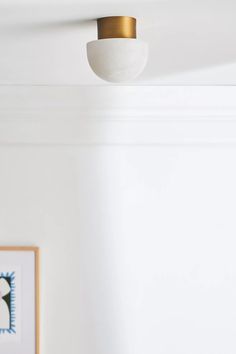 a white ceiling with a gold light fixture and pictures on the wall in front of it