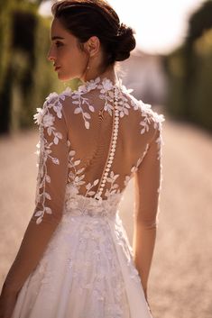 the back of a woman's wedding dress, with white flowers and pearls on it