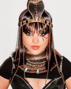 a woman wearing an egyptian headdress with chains and jewels on her face is looking at the camera