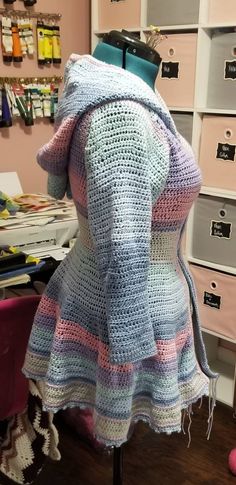 a crocheted jacket on a mannequin in a room with many drawers