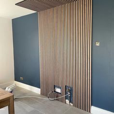 a room with blue walls and wooden slats on the wall, while an electrical outlet is plugged in