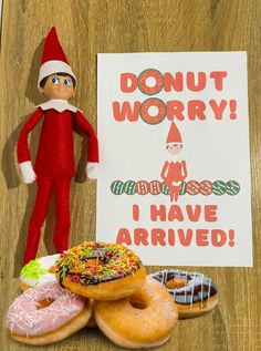 an elf is standing next to donuts and a sign