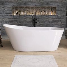 a white bath tub sitting on top of a wooden floor next to a wall mounted fireplace