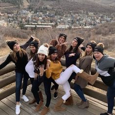 a group of young women posing for a photo on a wooden deck with mountains in the background