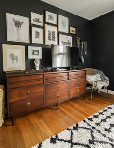 a bedroom with pictures on the wall and a dresser in front of it, along with a bed