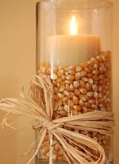 a glass jar filled with corn and a lit candle