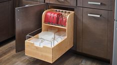 an open dishwasher drawer in the middle of a kitchen with wooden cabinets and drawers