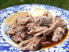 a blue and white plate topped with meat covered in gravy