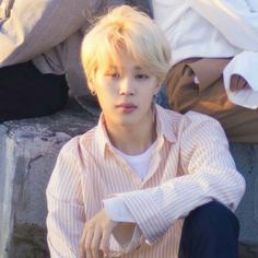 a young man sitting on top of a stone bench