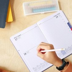 a person is writing on a notebook with a pencil in their hand and an eraser next to it