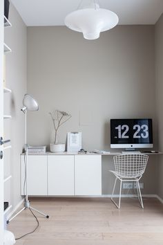 a television sitting on top of a white cabinet next to a desk with a lamp