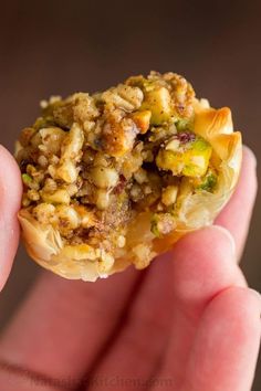 a hand holding a piece of food in it's left hand, with stuffing on top