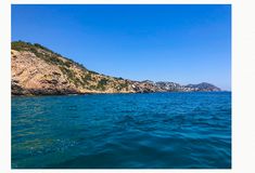 the water is very blue and there are some hills in the distance on the other side