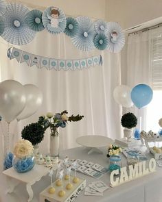 a table topped with balloons and cake next to a white wall covered in blue decorations