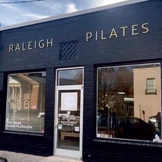 the front of a building with two windows and signs on it that say, rallegh pilates