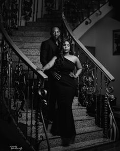 a man and woman are standing on the stairs in black and white, with their arms around each other