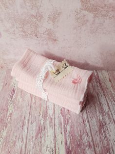 a pink cloth with lace on it sitting on top of a wooden floor next to a wall