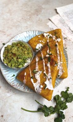 two quesadillas are on a plate with guacamole and salsa