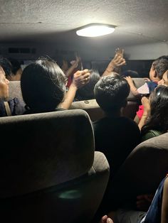 people are sitting in the back of a car with their hands up and one person is reaching for something