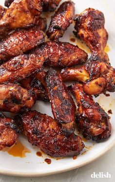 chicken wings on a white plate covered in sauce