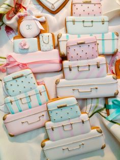 decorated cookies in the shape of suitcases on a white tablecloth with pink and blue ribbons