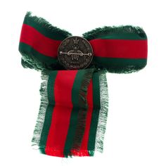 a red, green and black scarf with a coin on it's end in the center