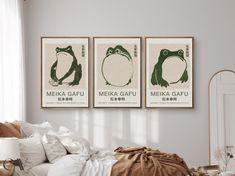 three green frog posters hanging on the wall above a bed in a room with white walls