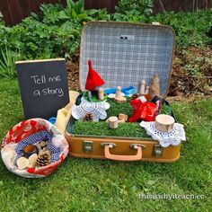 an open suitcase sitting in the grass next to a sign that says tell me a story