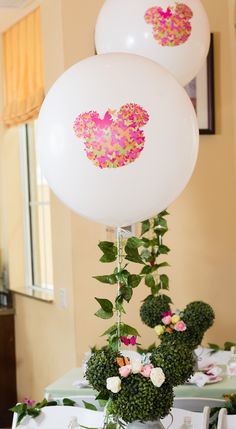 two white balloons with pink and green confetti on them sitting on top of a table