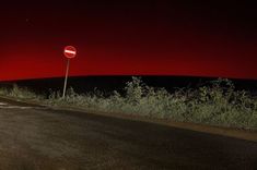 an empty road at night with a red sky