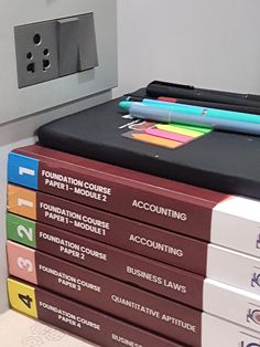 a stack of books sitting on top of each other in front of a metal box