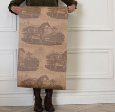 a person holding up a large piece of fabric with horses on it