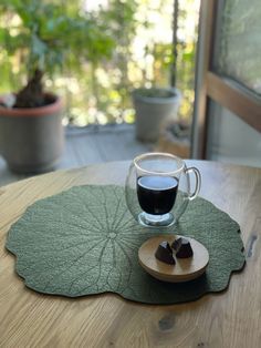 a cup of coffee sitting on top of a wooden table next to a piece of cake